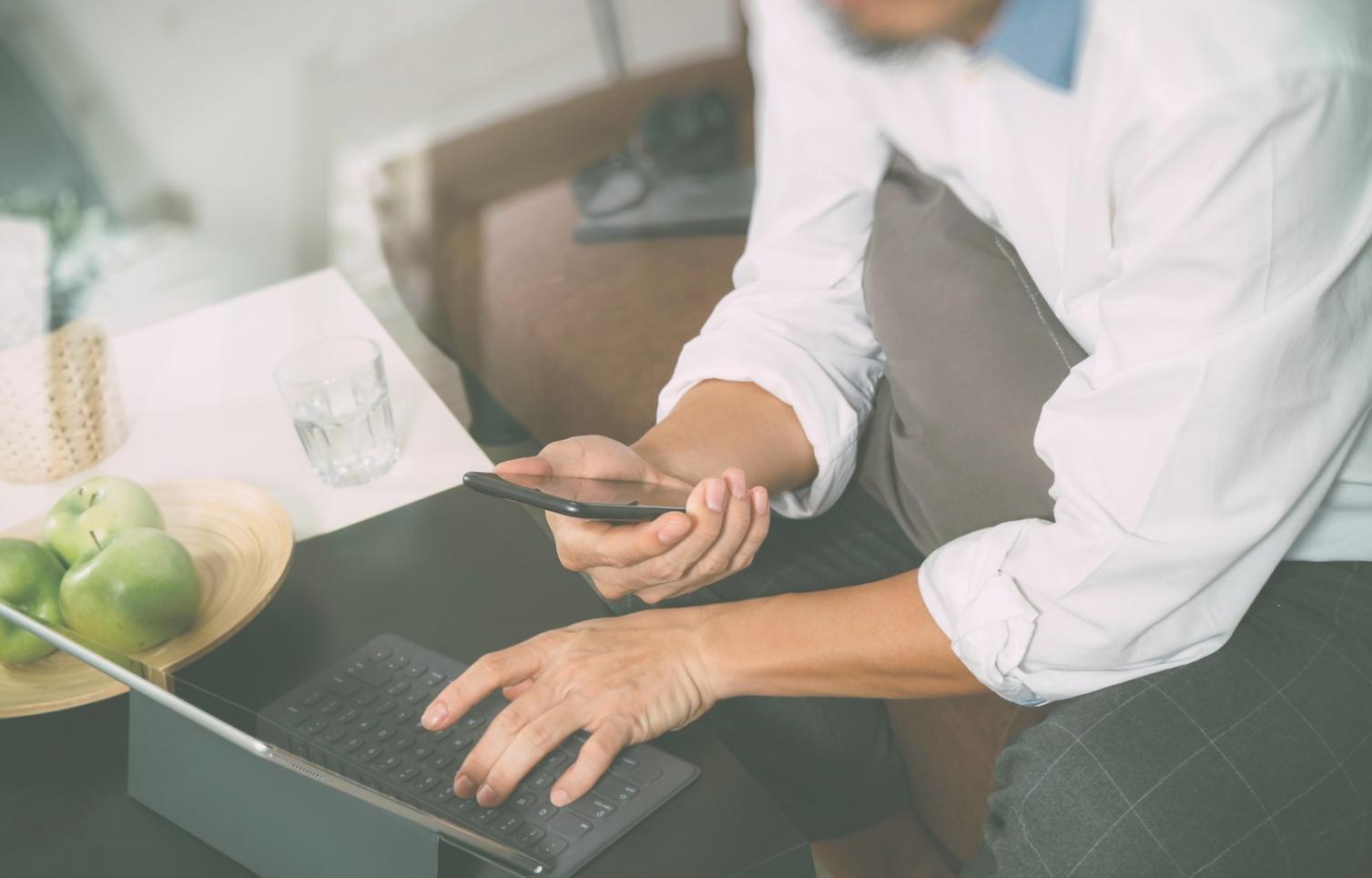 Person reviewing financial documents with laptop in natural lighting